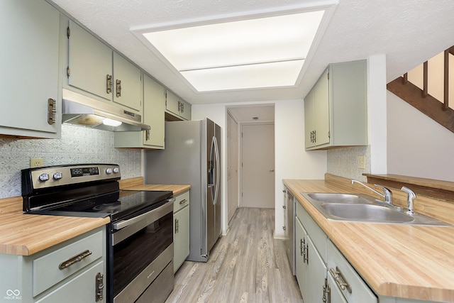 kitchen with light wood-style flooring, butcher block countertops, stainless steel appliances, under cabinet range hood, and a sink