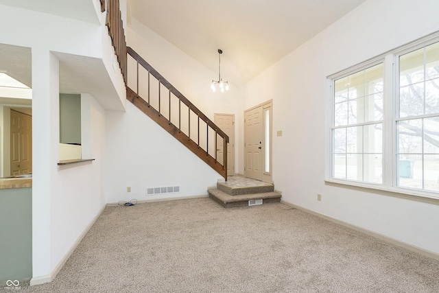 unfurnished living room featuring stairway, plenty of natural light, carpet flooring, and visible vents