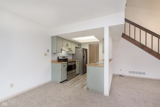 kitchen with under cabinet range hood, appliances with stainless steel finishes, visible vents, and light colored carpet