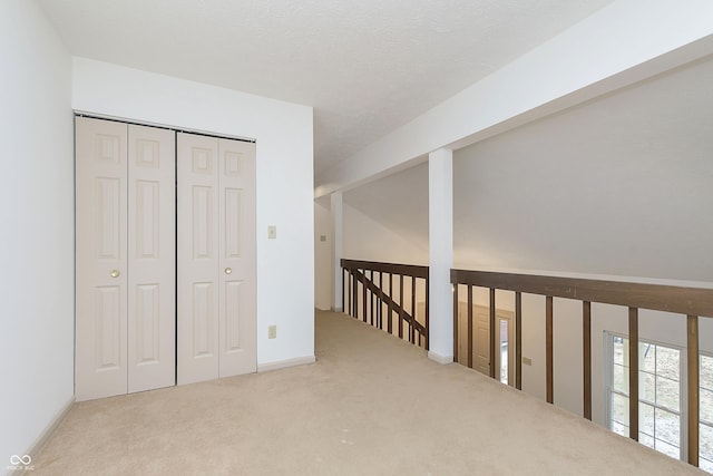 corridor featuring a textured ceiling and carpet flooring