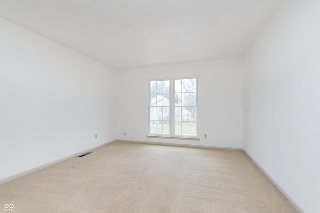 unfurnished room with baseboards, visible vents, and light colored carpet