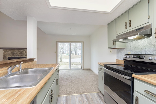 kitchen featuring wooden counters, decorative backsplash, a sink, stainless steel range with electric stovetop, and under cabinet range hood