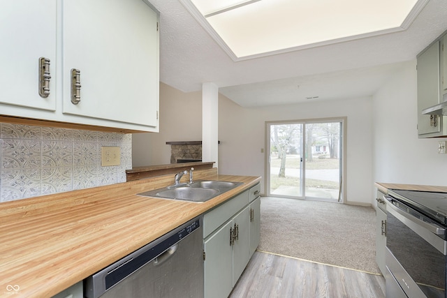 kitchen with light wood-style floors, appliances with stainless steel finishes, light countertops, and a sink