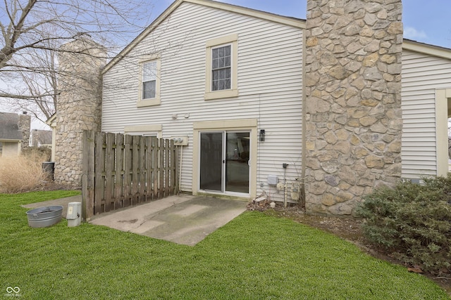 rear view of house featuring a patio area, a chimney, fence, and a yard