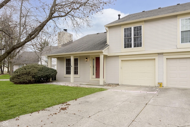 tri-level home featuring a front yard, driveway, a chimney, and an attached garage