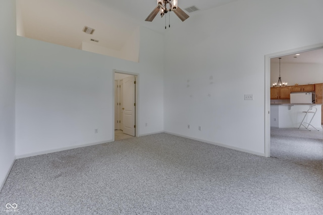 unfurnished room with high vaulted ceiling, visible vents, light carpet, and ceiling fan with notable chandelier