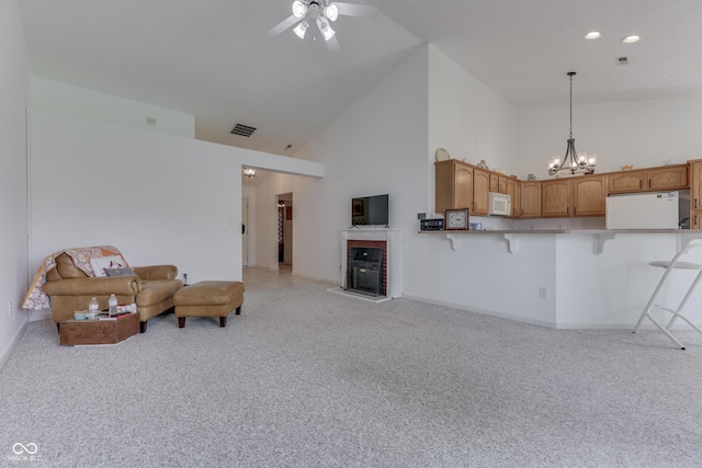 living area featuring visible vents, light colored carpet, a fireplace, high vaulted ceiling, and ceiling fan with notable chandelier