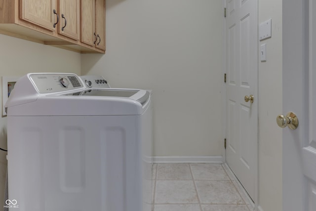 laundry area with light tile patterned floors, baseboards, washer and dryer, and cabinet space