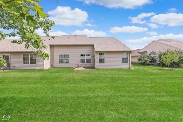 rear view of property featuring roof with shingles and a lawn