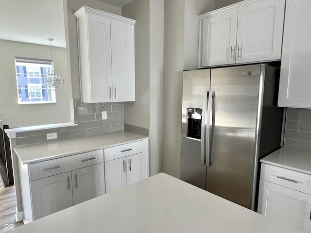 kitchen featuring white cabinetry, tasteful backsplash, stainless steel refrigerator with ice dispenser, and light countertops