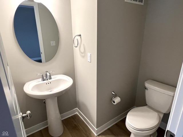 bathroom with baseboards, toilet, and wood finished floors