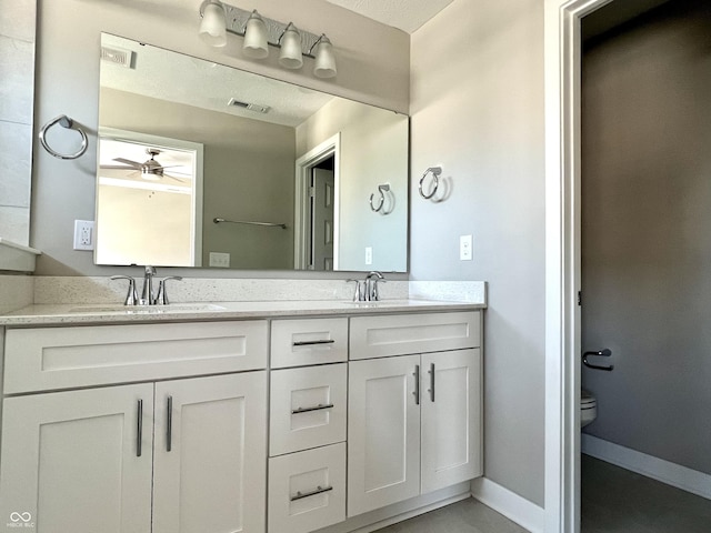 bathroom with double vanity, visible vents, toilet, and a sink