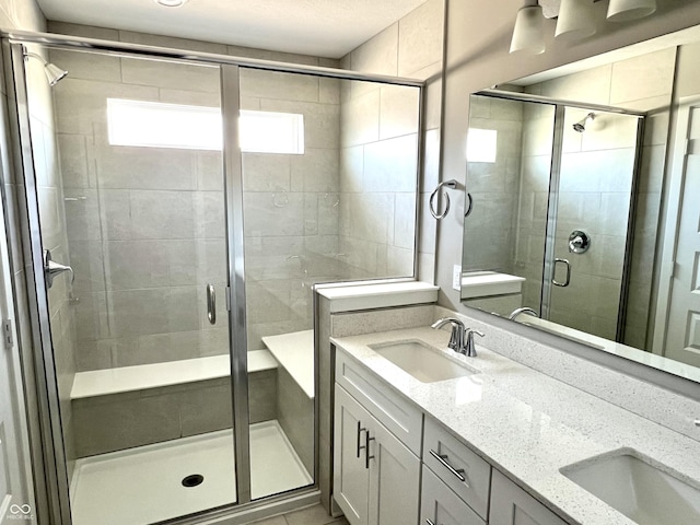 full bath with double vanity, a stall shower, and a sink