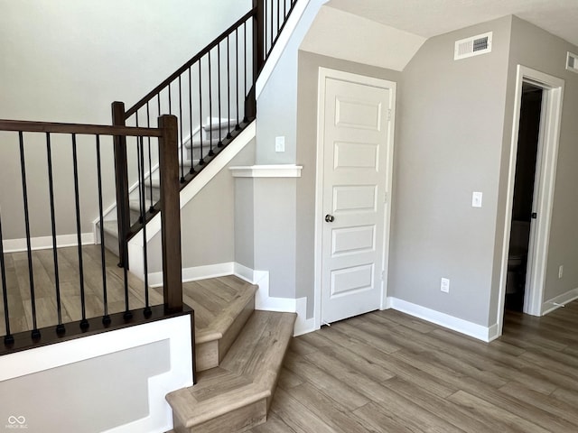 stairway with visible vents, wood finished floors, and baseboards