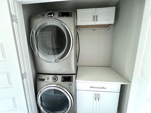 clothes washing area with cabinet space and stacked washer and clothes dryer