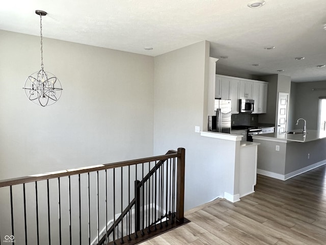 interior space with baseboards, light wood-type flooring, white cabinets, stainless steel appliances, and a sink