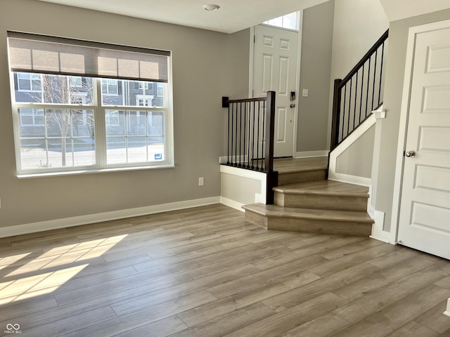 entrance foyer featuring stairway, a healthy amount of sunlight, baseboards, and wood finished floors