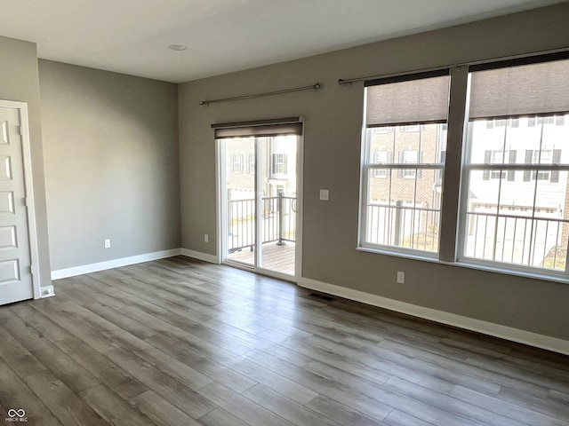 spare room featuring visible vents, dark wood-type flooring, and baseboards