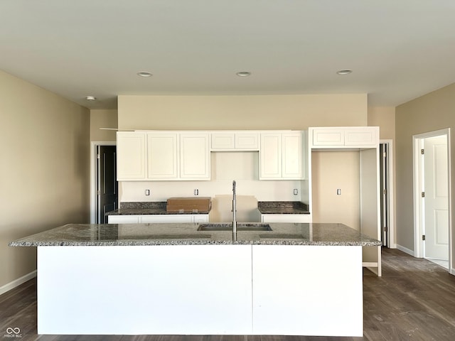 kitchen with dark wood-style floors, baseboards, a sink, white cabinets, and a center island