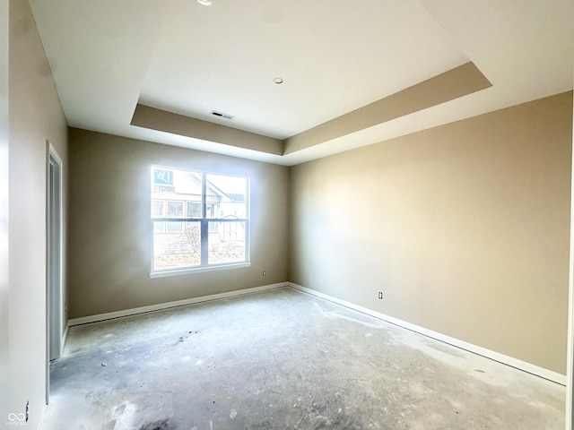 unfurnished room with visible vents, baseboards, and a tray ceiling