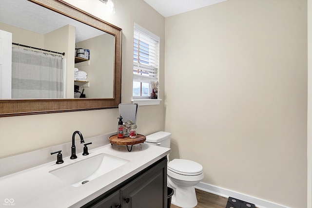 bathroom with baseboards, vanity, toilet, and wood finished floors