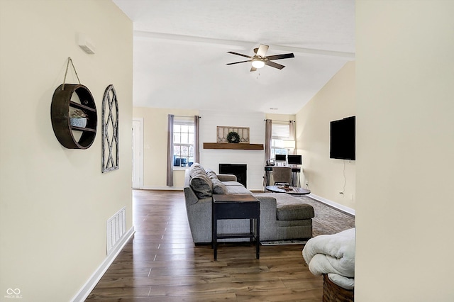 living room featuring a fireplace, lofted ceiling, visible vents, ceiling fan, and wood finished floors