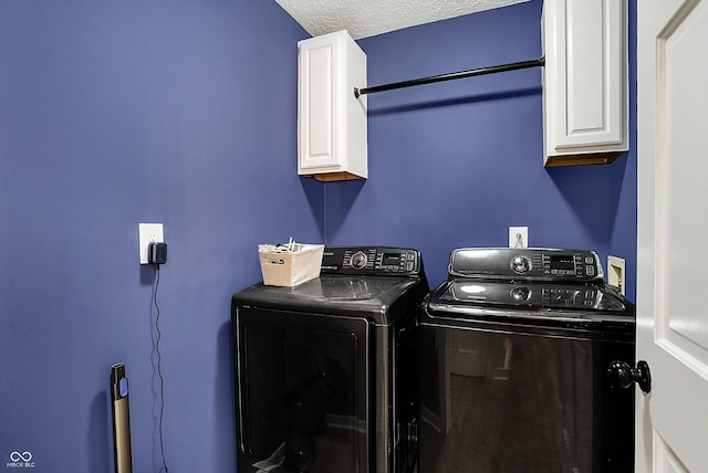 washroom featuring cabinet space, a textured ceiling, and washing machine and clothes dryer