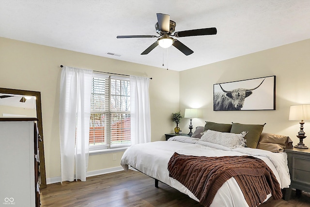 bedroom featuring a ceiling fan, visible vents, baseboards, and wood finished floors