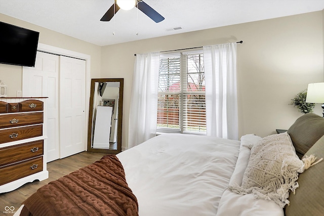 bedroom featuring ceiling fan, a closet, visible vents, and wood finished floors