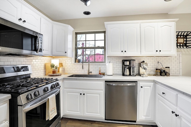 kitchen featuring appliances with stainless steel finishes, white cabinetry, a sink, and decorative backsplash