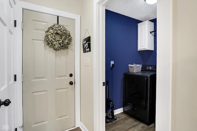 laundry area featuring a textured ceiling, wood finished floors, baseboards, cabinet space, and washer / dryer