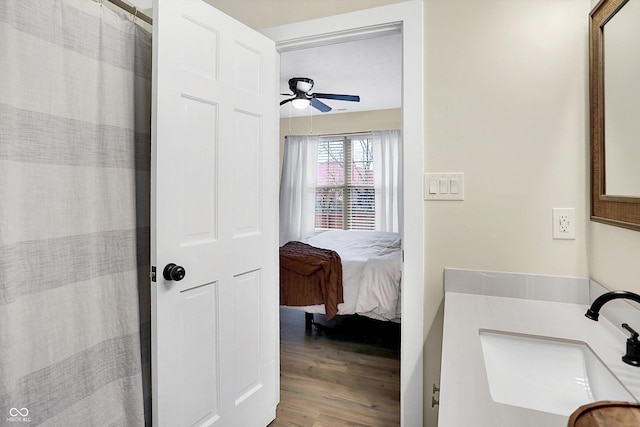 ensuite bathroom with wood finished floors, a sink, a ceiling fan, and a shower with curtain