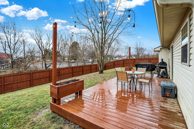 wooden deck with a fenced backyard, outdoor dining area, and a lawn