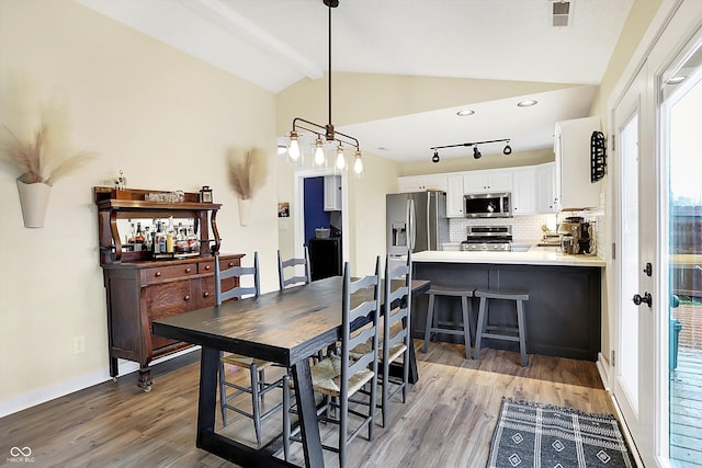 dining area featuring visible vents, lofted ceiling with beams, and wood finished floors