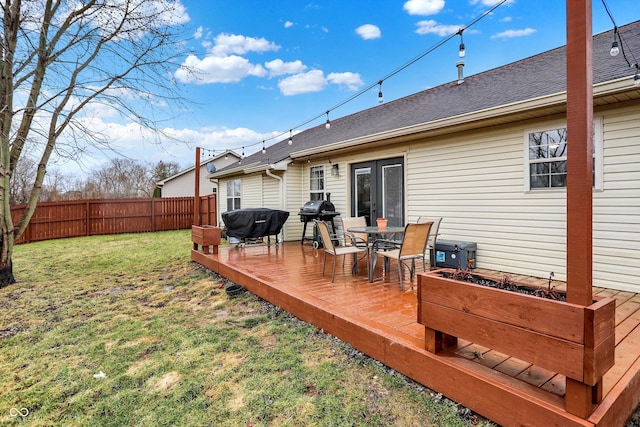 wooden terrace featuring a lawn, grilling area, and fence