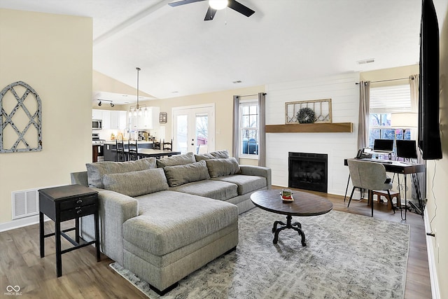 living room featuring lofted ceiling with beams, a fireplace, wood finished floors, visible vents, and a ceiling fan