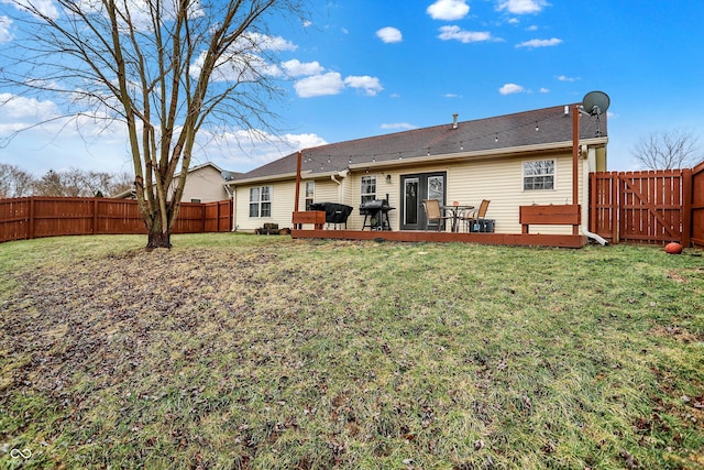 rear view of house with a fenced backyard, a lawn, and a wooden deck