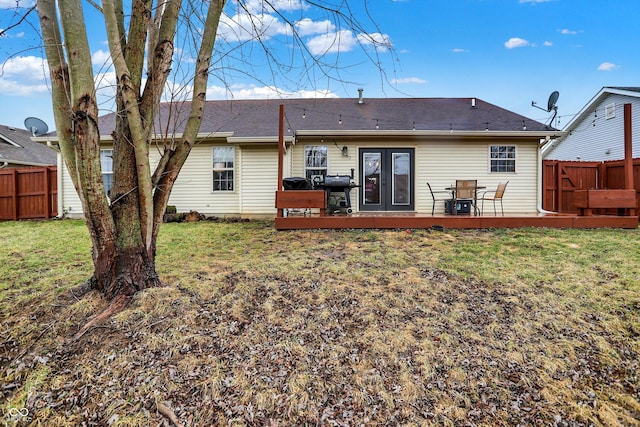 rear view of house featuring a deck, french doors, a lawn, and fence