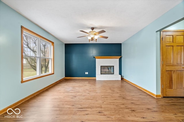 unfurnished living room featuring ceiling fan, baseboards, and wood finished floors