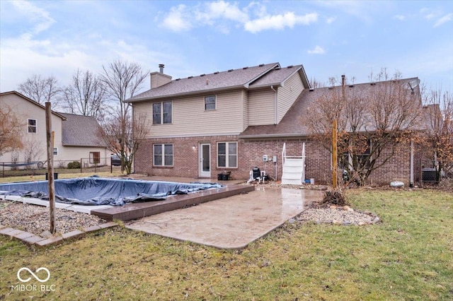 rear view of house with brick siding, fence, a chimney, a yard, and a patio area