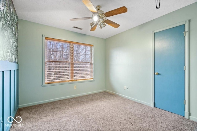 carpeted spare room with visible vents, baseboards, and a textured ceiling