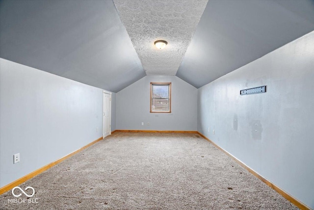 additional living space featuring carpet flooring, a textured ceiling, baseboards, and vaulted ceiling