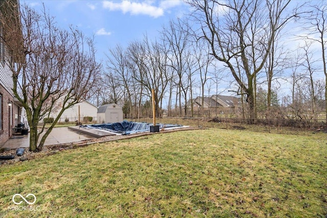 view of yard with an outbuilding, a shed, a fenced backyard, and a patio