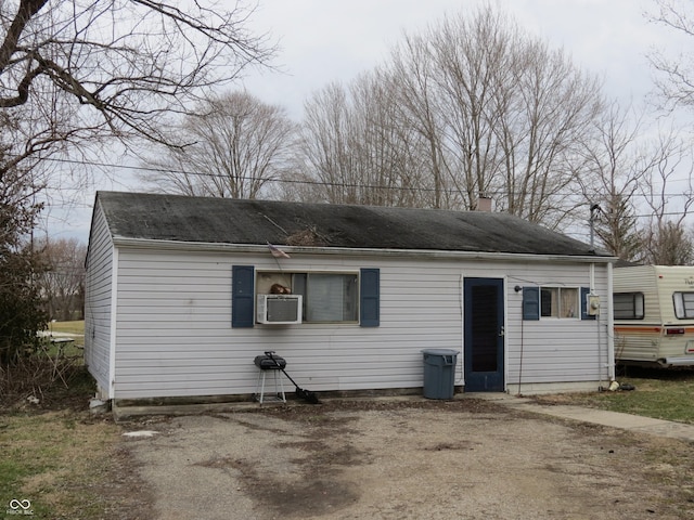 view of front of home featuring driveway, a chimney, cooling unit, and roof with shingles