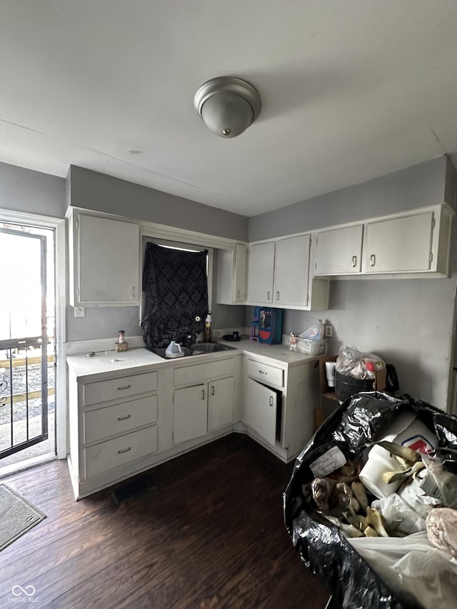 kitchen with dark wood-style floors, light countertops, a sink, and white cabinetry