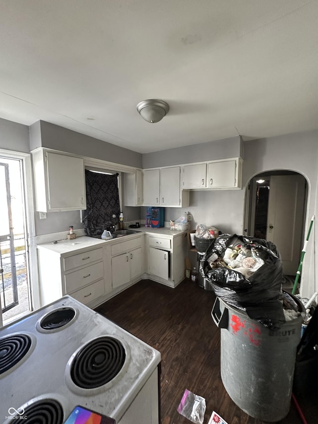 kitchen with white range with electric stovetop, dark wood-style flooring, light countertops, white cabinetry, and a sink