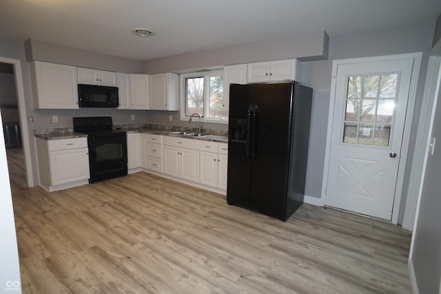 kitchen featuring black appliances, a sink, light wood-style flooring, and white cabinets