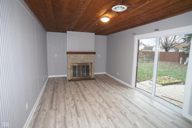 unfurnished living room featuring wood ceiling, a brick fireplace, light wood-style flooring, and baseboards