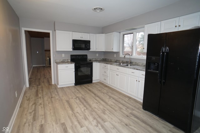 kitchen with a sink, visible vents, white cabinetry, light wood-type flooring, and black appliances