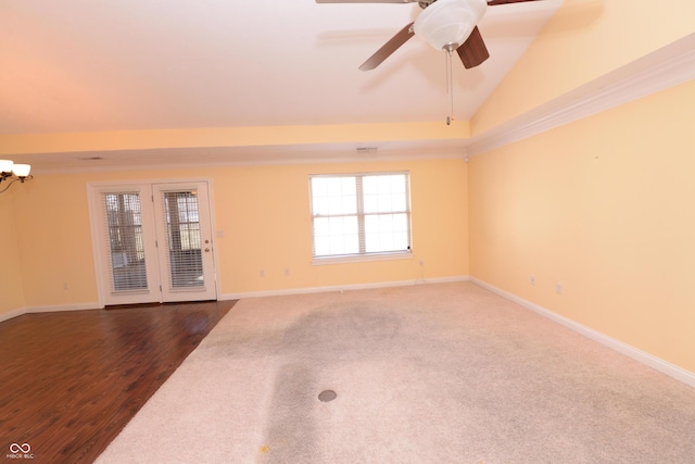 empty room with vaulted ceiling, dark wood-type flooring, ceiling fan with notable chandelier, and baseboards